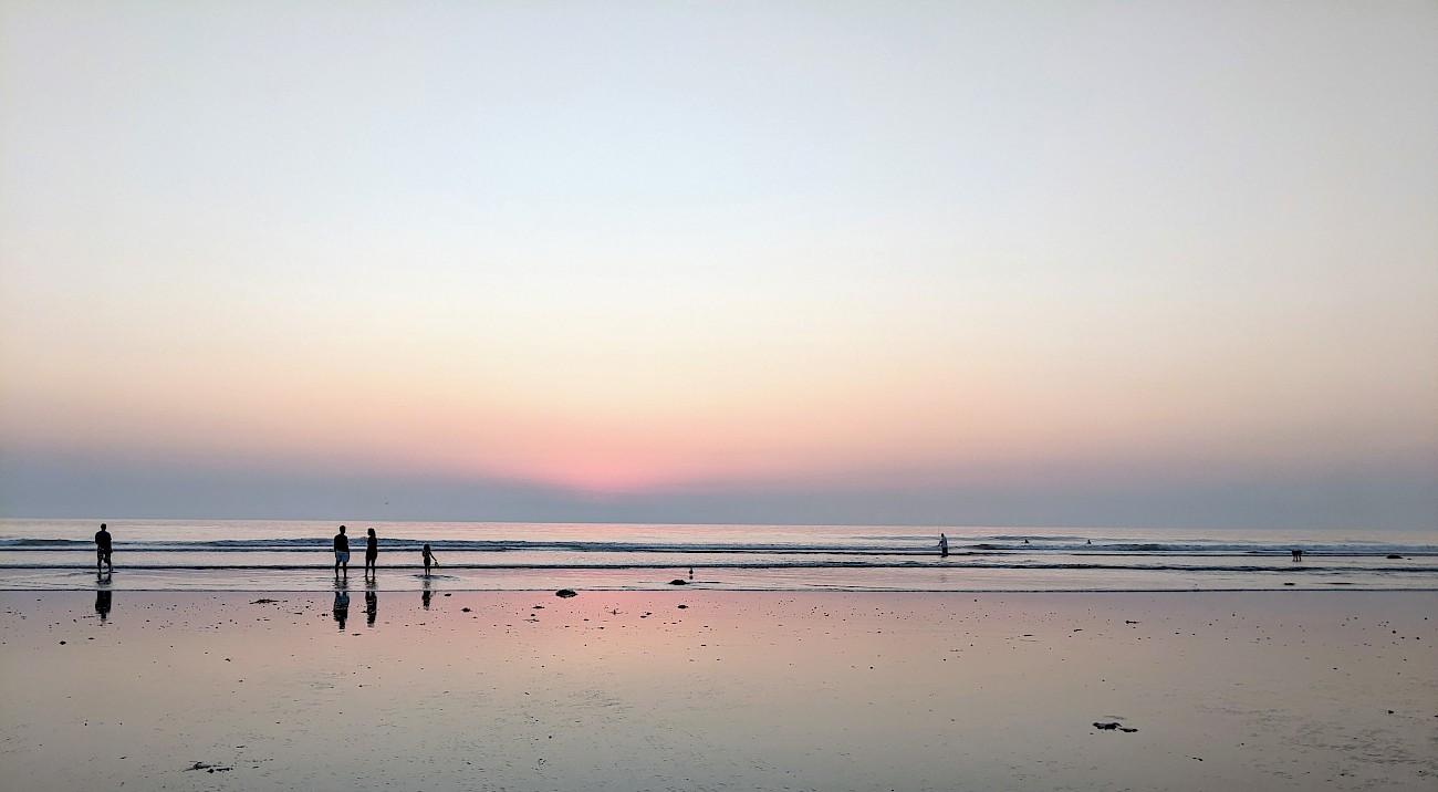 pink sky just after sunset reflected in the wet sand