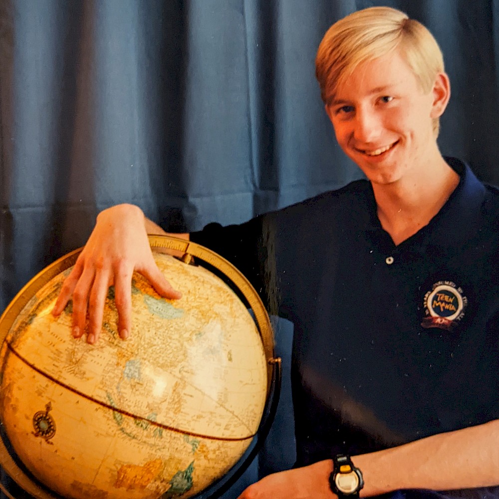 me posing next to a globe with my hand over the top of it