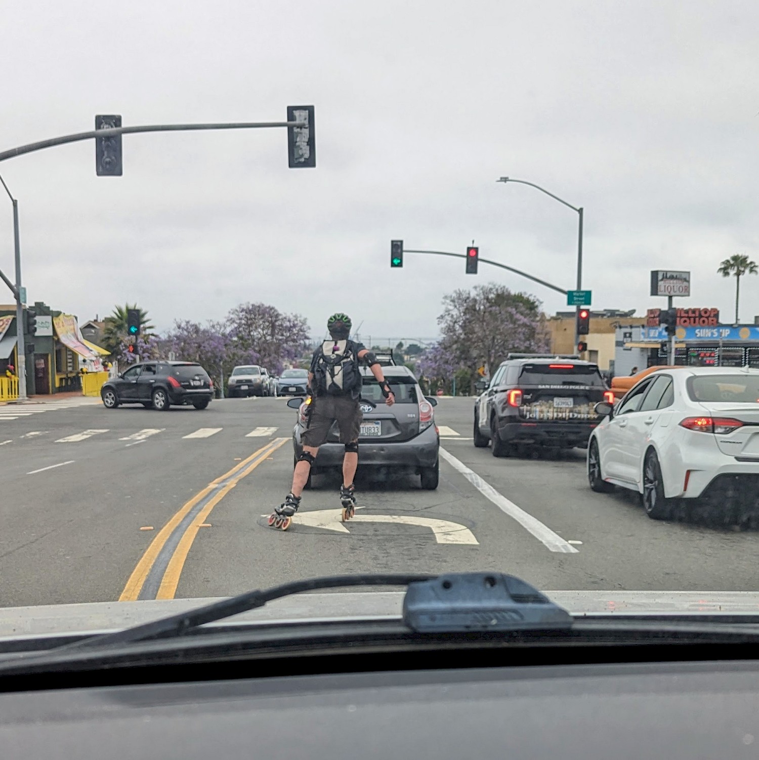 A rollerblader skating in the left hand turn lane in front of me while I was driving. In the lane next to us is a cop.