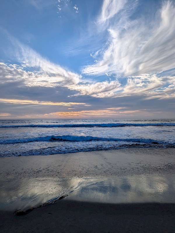 Ocean waves and a blue sky with wispy clouds